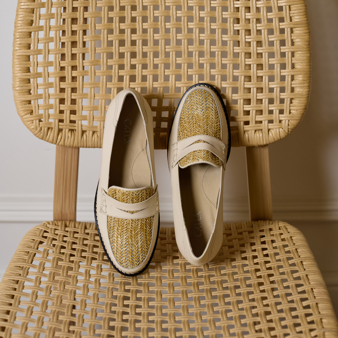 Nadia Buttermilk Leather Raffia Loafers displayed on a woven chair